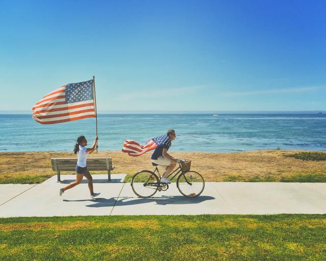 child running after father holding American flag going to Memorial Day Activities