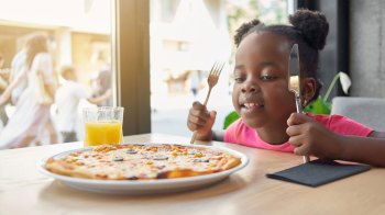 girl enjoying pizza at restaurants where kids eat free