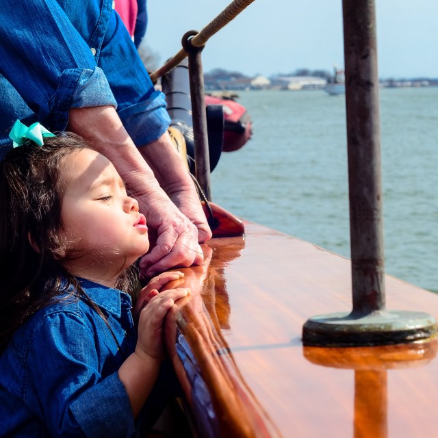 girl pursing lips standing near edge of boat