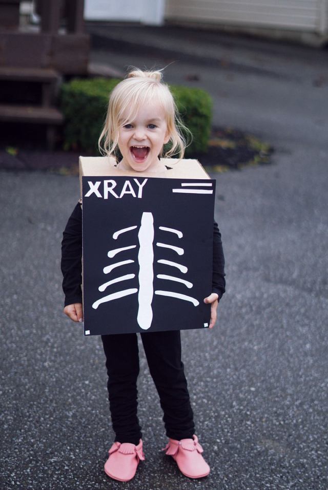 A little girl is dressed up for Halloween like an Xray using a cardboard box