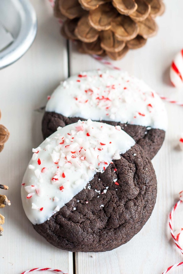 Two cookies sit on a counter with one half of each cookie white with candy cane sprinkles