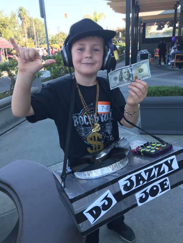 A boy dressed up like a DJ booth using an old box