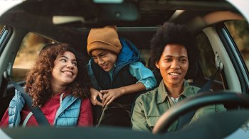 family of three in car road trip in the fall