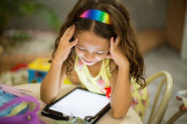 little girl on ipad looking at a YouTube channel