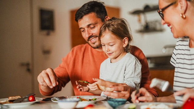 a little girl at the table with her parents playing a game that's the best picky eating hack