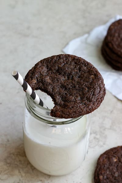A brown toffee nutella cookie sits on top of a glass of milk