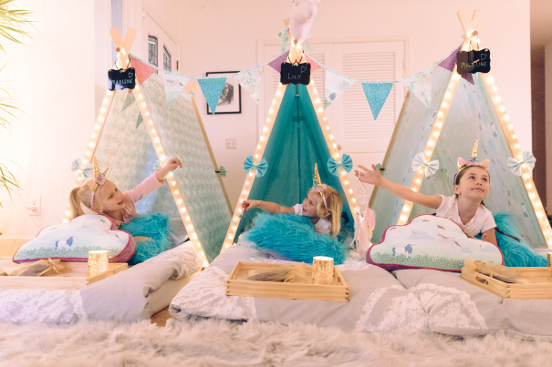 Three teepee filled with party-goers sit on the floor awaiting a sleepover