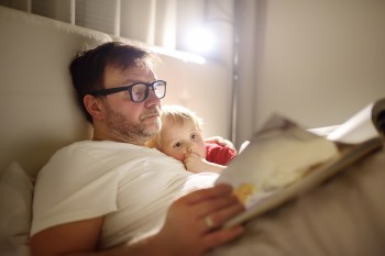 parent and child reading in bed