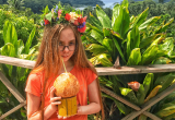 girl with flower headband drinks tropical drink from coconut