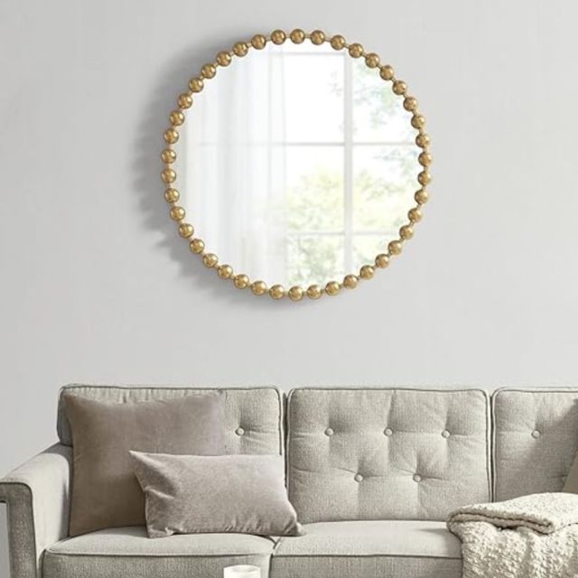 gold beaded round mirror hanging on wall
