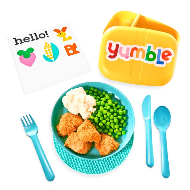 A blue bowl filled with a children's meal alongside utensils and other welcome goodies from Yumble, a meal delivery service for children