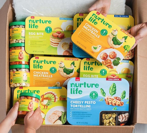 Children reach into a box filled with snacks and meals from Nurture Life meal delivery service