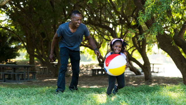 little girl and dad playing with a beach ball outside
