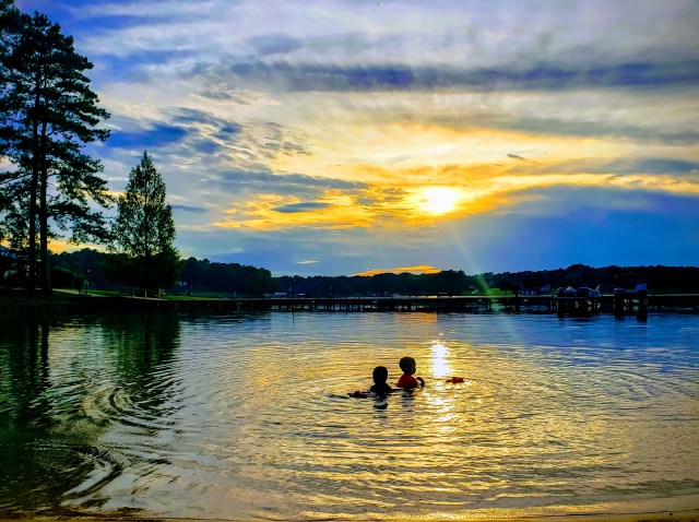 two children swimming in the lake at sunset