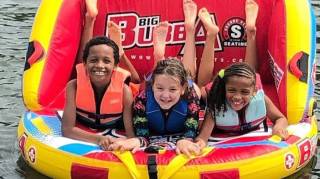 three kids are tubing at a local lakes near Atlanta on a sunny day