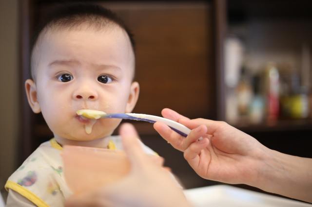 a picture of a baby eating food that came from a baby food maker