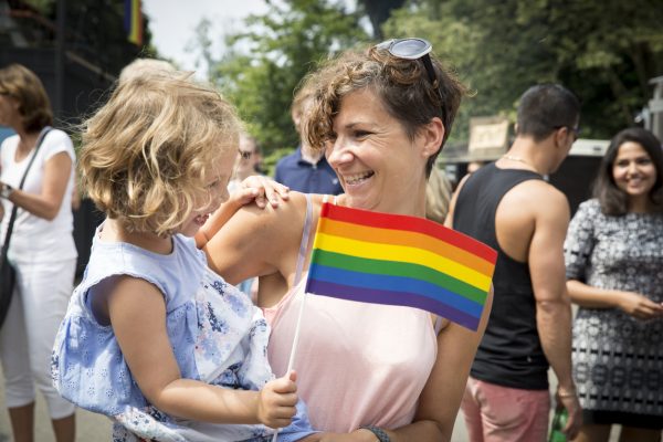 mother with her daughter at a Pride parade waving a rainbow flag
