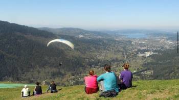 people watch paragliders sail down from poo poo point after a hike
