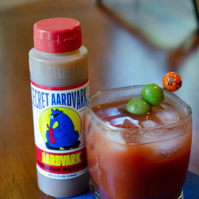 bottle of hot sauce next to a bloody mary