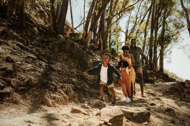 a family goes hiking in the wood, led by a joyful little boy