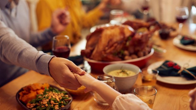 child and parent holding hands at the Thanksgiving table