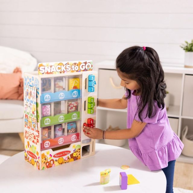 little girl playing with wooden vending machine toy