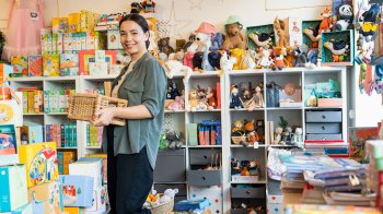 woman standing in children's toy store with toys and dolls in the background