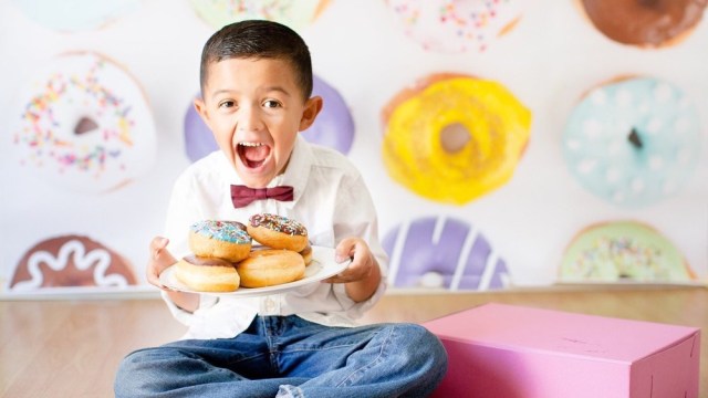 A boy holds a plate of donuts