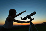person pointing at the sky with telescope stargazing