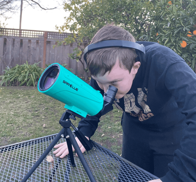 kid looking through telescope stargazing