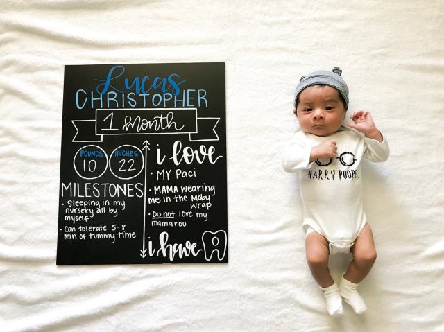 a baby lying next to a chalkboard with his age, size, milestones and things he loves for a monthly baby photo