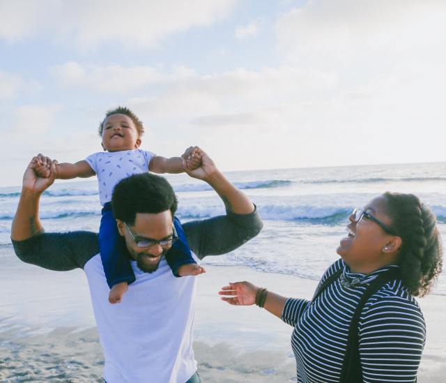mom, dad and baby laughing on the beach