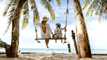 mom and son on a swing enjoying beach vacation
