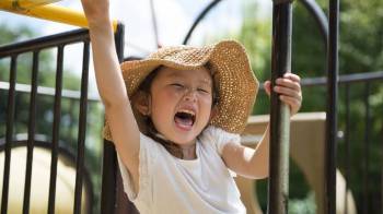 A girl on a playground laughing at summer jokes for kids