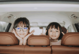 Asian kids looking out window of car on family road trip