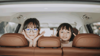 Asian kids looking out window of car on family road trip