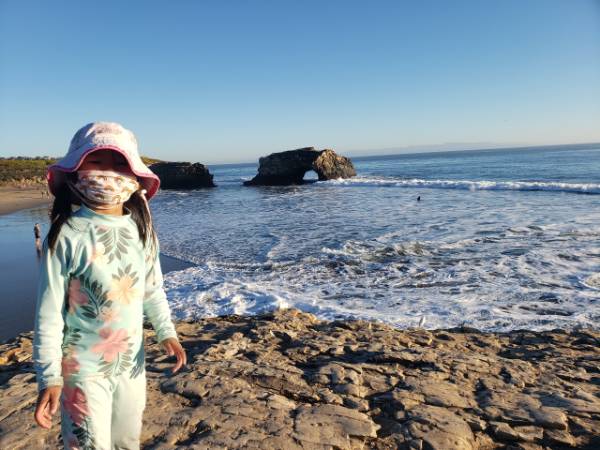 A girl stands in front of the Natural Bridges State beach