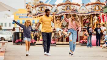 family walking by amusement park rides at San Diego's Belmont Park