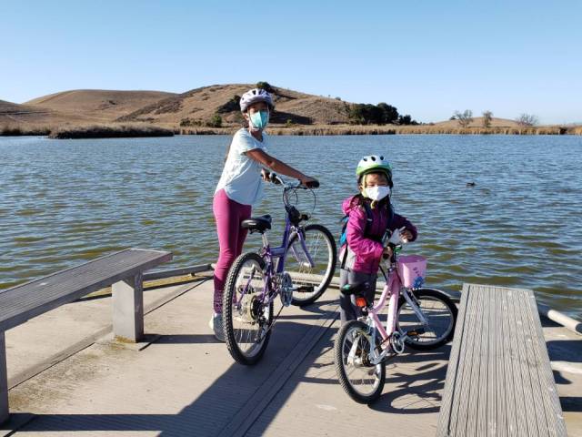 two girls bike by a pond