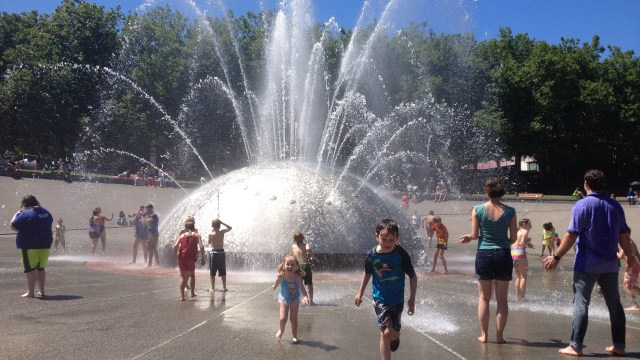 Kids run through the international fountain at Seattle sparyparks wading pools