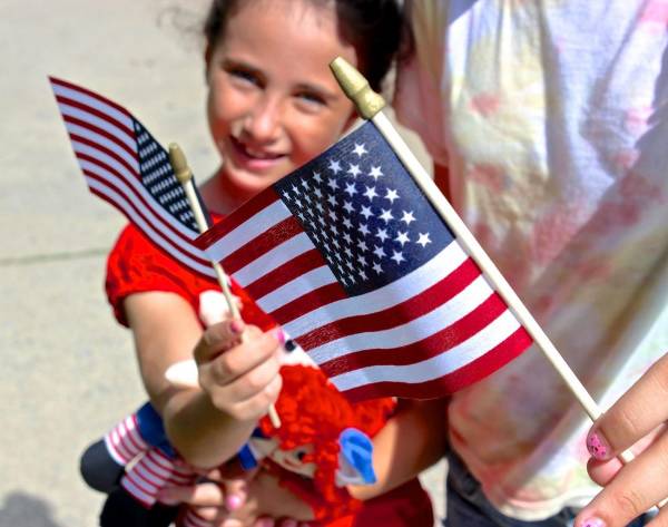 A girl waves a flag at a July 4th parade