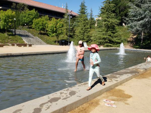 Two girls splash in a fountain at Stanford University