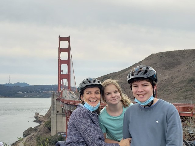A mother and her kids pose at the Golden Gate Bridge after biking across