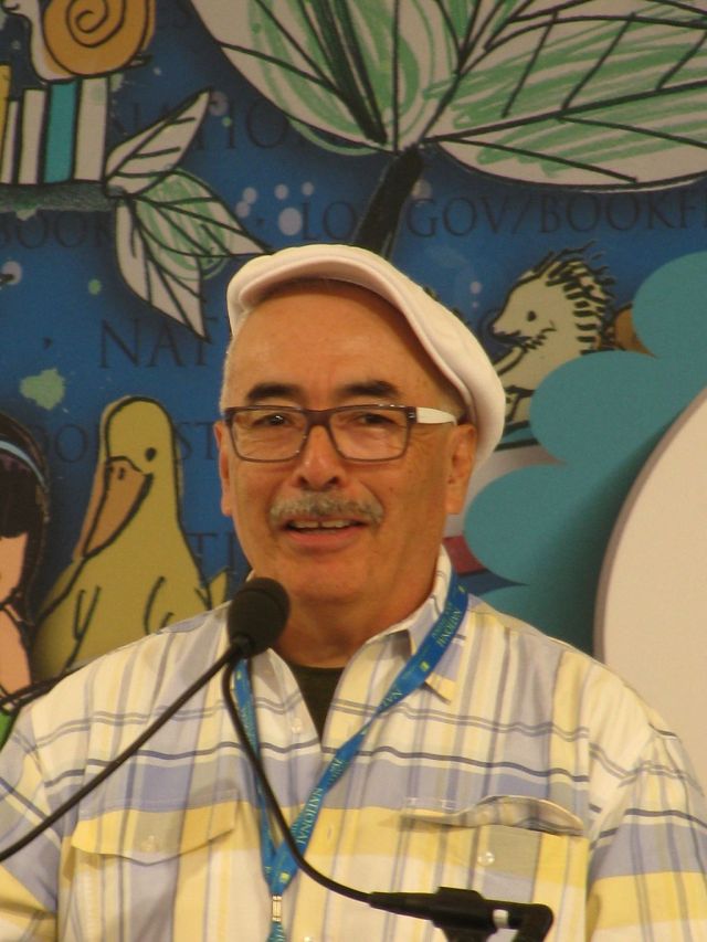 A portrait of LatinX hero Juan Felipe Herrera, the 21st United States Poet Laureate from 2015 to 2017, in front of a hand-drawn background