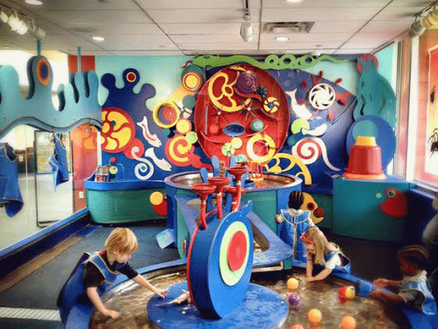 Children play with colorful water features at the Brooklyn Children's Museum's Totally Tots section. 