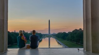 family with baby on Lincoln Memorial looking at Washington Memorial at sunrise