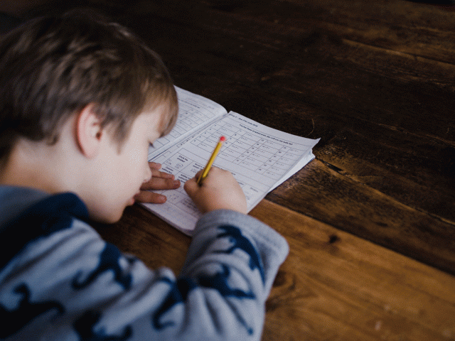 A boy writes a poem in his workbook as part of a new family tradition