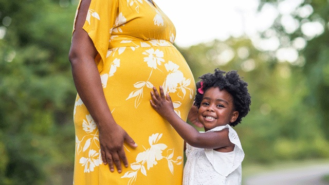 a pregnant mom dressed in a yellow flowered dress on her way to a baby sprinkle shower 
