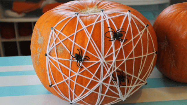 A no-carve pumpkin is decorated to look like a spider web