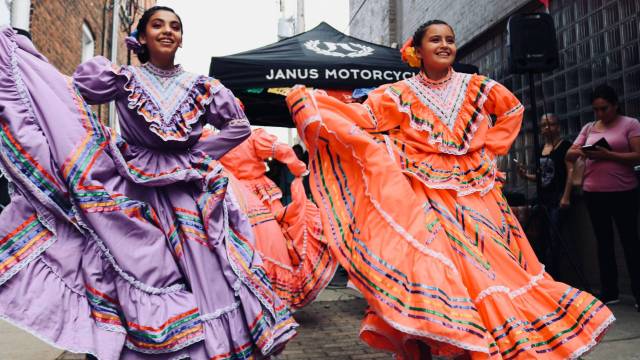 two women twirl traditional latinx dresses during a hispanic heritage month celebration